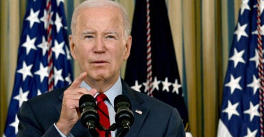 President Joe Biden speaks at a podium with US flags in background