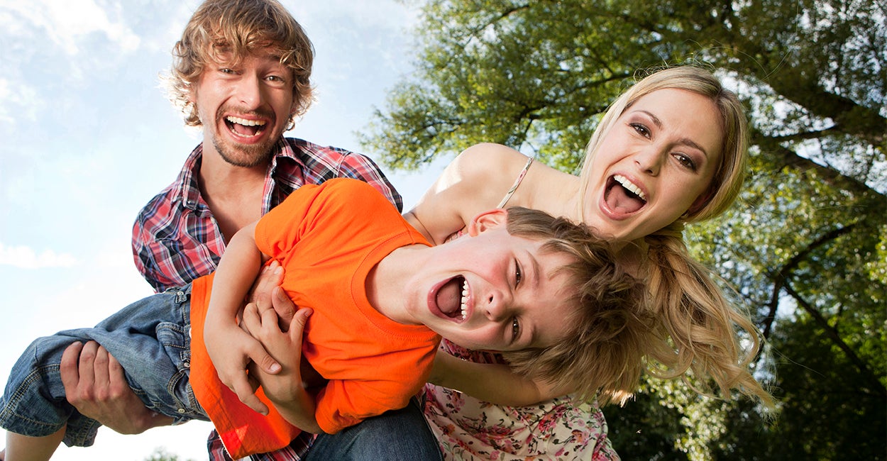 Laughing father, mother, and young son playing outdoors