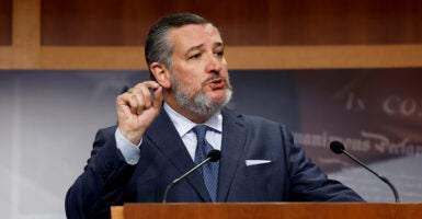 Ted Cruz speaks into a microphone wearing a black suit.