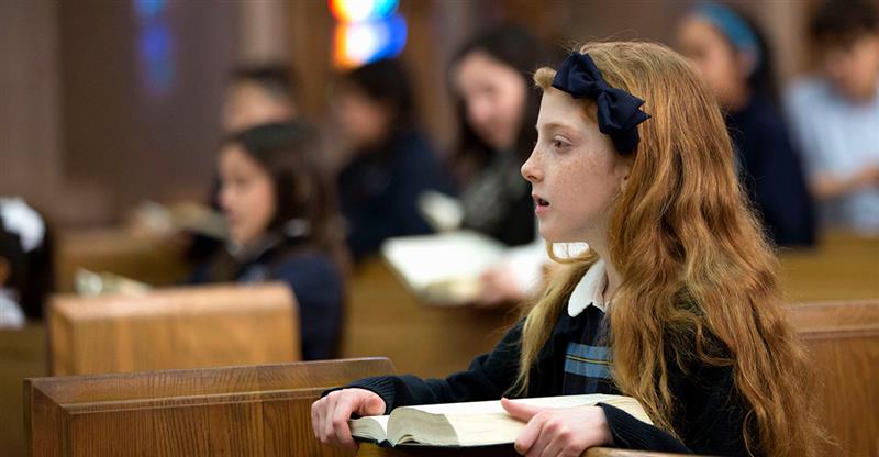 Students in pews learning at a Catholic school.