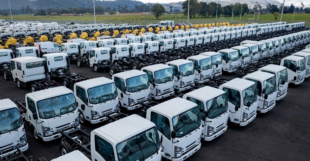 A row of tractor-trailer trucks parked at a dealership.