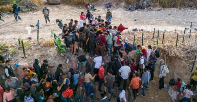 Hundreds of illegal immigrants crossing into the U.S. at a hole cut into barbed wire fencing.