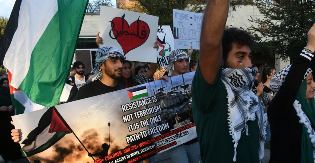 students rally in support of Palestine, holding up signs and the Palestinian flag