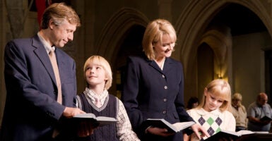 A father, a mother, and their young son and daughter standing in a pew at a church