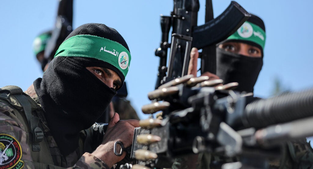 Two Palestinian fighters with the armed wing of Hamas holding machine guns