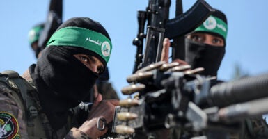 Two Palestinian fighters with the armed wing of Hamas holding machine guns