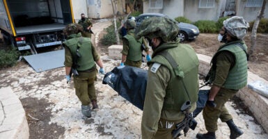 Four Israel Defense Force soldiers carry a body bag of a civilian killed in the attacks by Hamas.