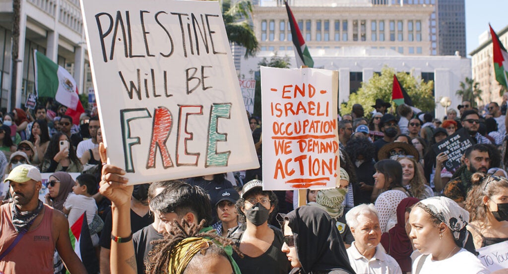 Protesters hold Palestinian flags and signs reading "Palestine will be free" and "end Israeli occupation"