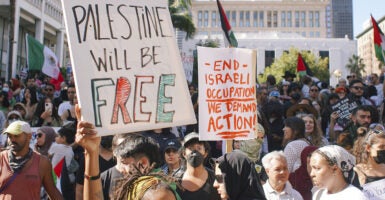 Protesters hold Palestinian flags and signs reading 