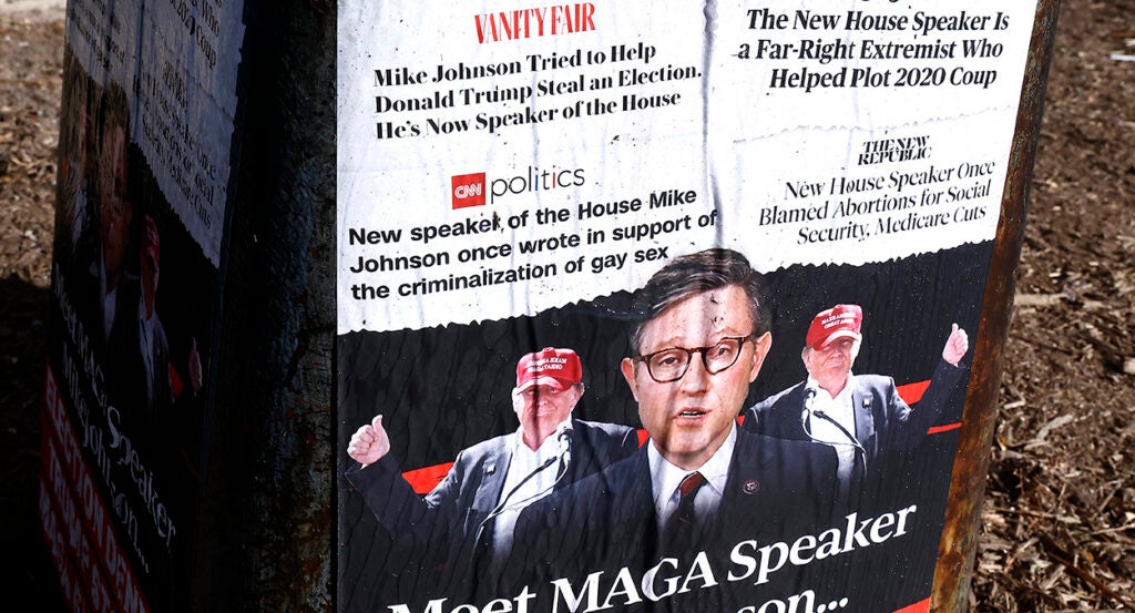 Posters outside in Washington, D.C., cite alarmist headlines about House Speaker Mike Johnson