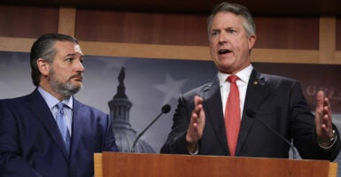 Roger Marshall speaks into a podium, Ted Cruz listens