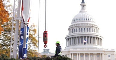 A construction worker stands with a crane in front of the U.S. Capitol