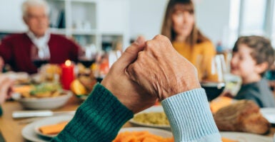 family prayer around a table holding hands.