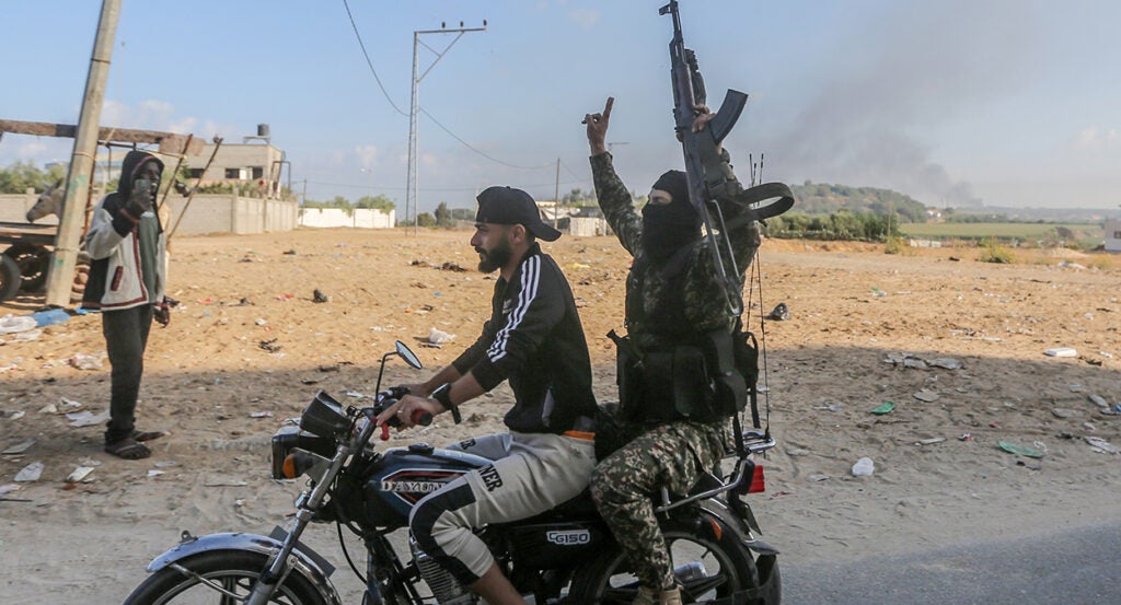 A Hamas terrorist celebrates on a motorcycle, holding a machine gun