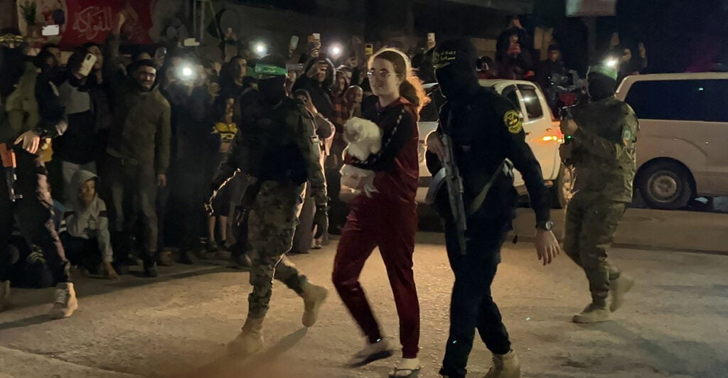 Terrorist carrying guns walk with a released hostage before turning her over to the Red Cross.