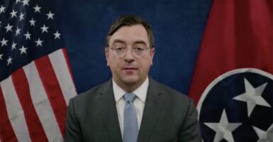 Tennessee Attorney General Jonathan Skrmetti in a suit with an American flag and a Tennessee flag behind him.