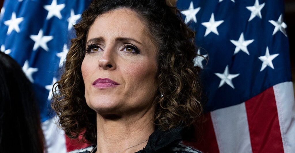 Rep. Julia Letlow, R-La., looks straight ahead while at a news conference with two large American flags behind her.