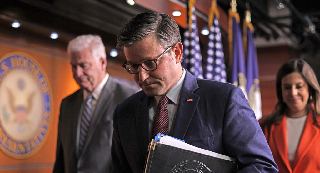 Mike Johnson in a blue suit walks with his head bowed