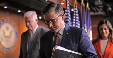 Mike Johnson in a blue suit walks with his head bowed