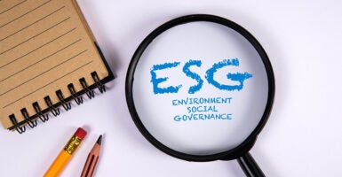 Magnifying glass on office desk highlighting the words “ESG – Environment, Social, Governance”