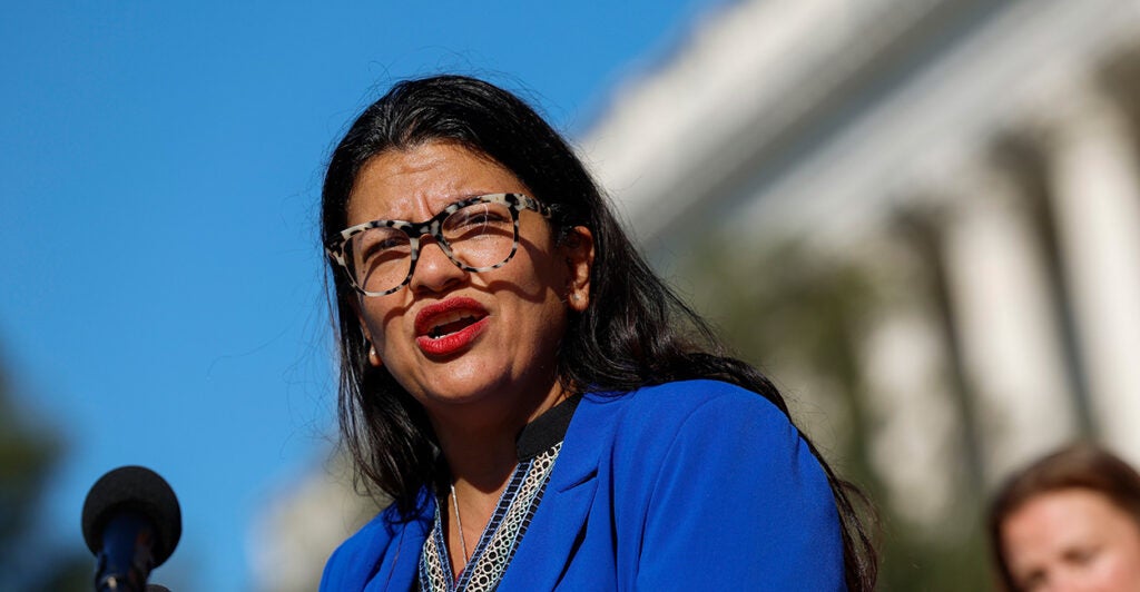 rashida tlaib speaks into a microphone wearing a blue suit