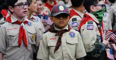 Boy scouts stand around aimlessly in uniform with American flags