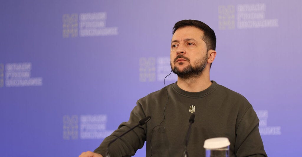 Ukrainian President Volodymyr Zelenskyy stands at a podium.