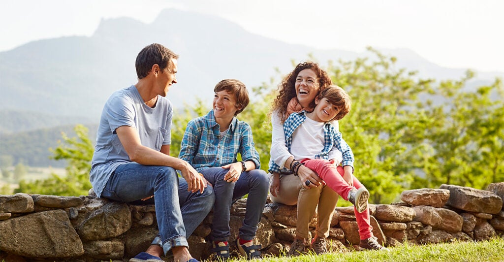 Young family with two children outside laughing.