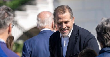 Hunter Biden in a black suit smiles as Joe Biden in a blue suit walks away