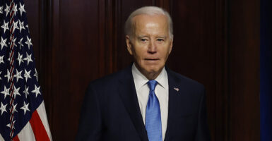 President Joe Biden in a black suit with an American flag pin and a blue tie.