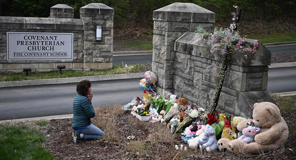 Woman prays in front of a memorial for the victims of the Nashville shooting at Covenant School