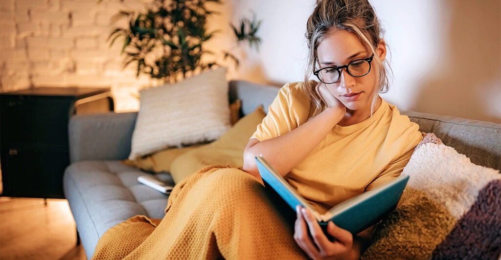 Young women reading a book at home on the sofa