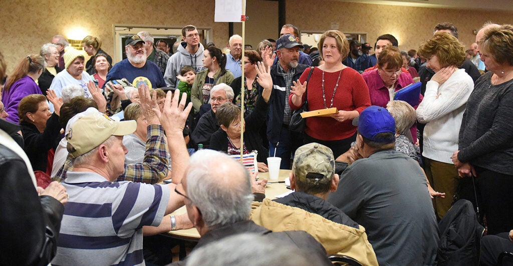 Iowa citizens sit and stand in a large room during the 2016 caucus.