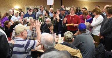 Iowa citizens sit and stand in a large room during the 2016 caucus.