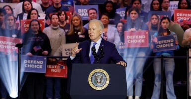 President Joe Biden speaks at a rally at a podium in a suit with a crowd behind him