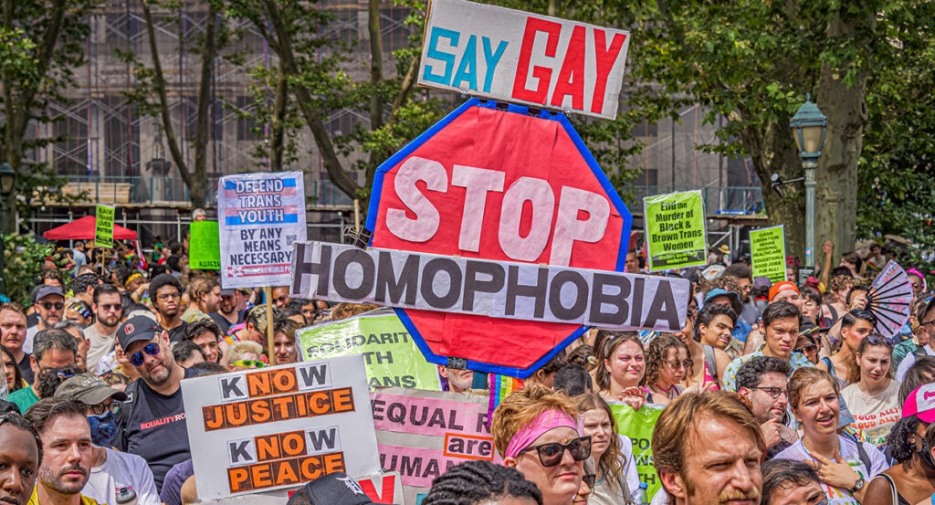 LGBTQ protesters hold signs reading "Stop homophobia," "say gay," "defend trans youth by any means necessary," and "end the murder of black & brown trans women."