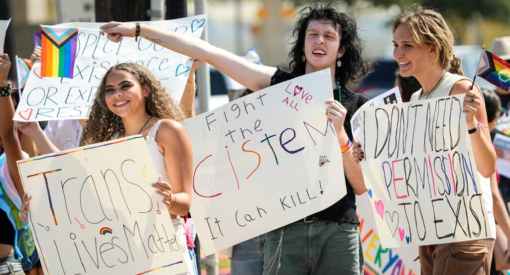 Young protesters hold transgender signs