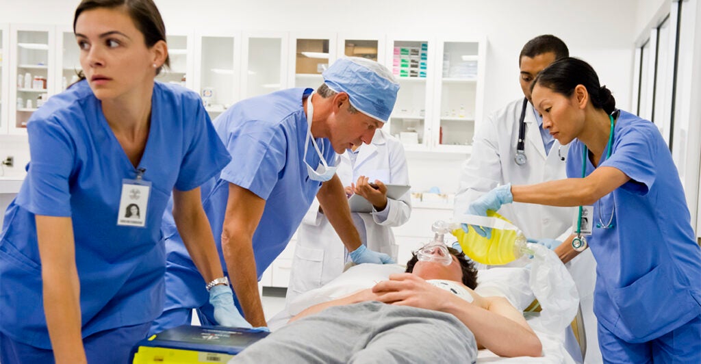 Five doctors and nurses working on a patient in the emergency room