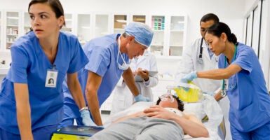 Five doctors and nurses working on a patient in the emergency room