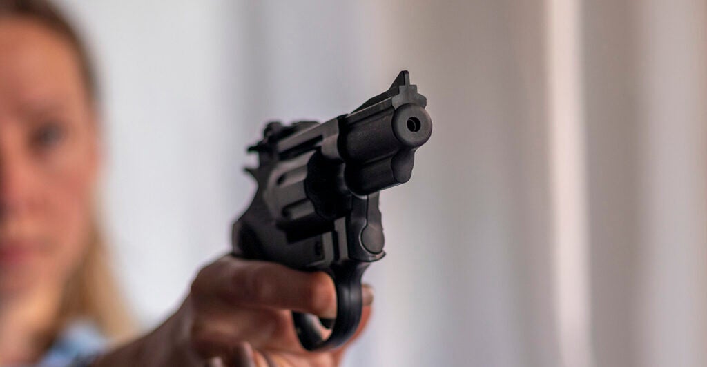 Blond woman pointing a black revolver