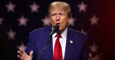 Former President Trump on stage at a Campaign Rally wearing a blue suit and red tie