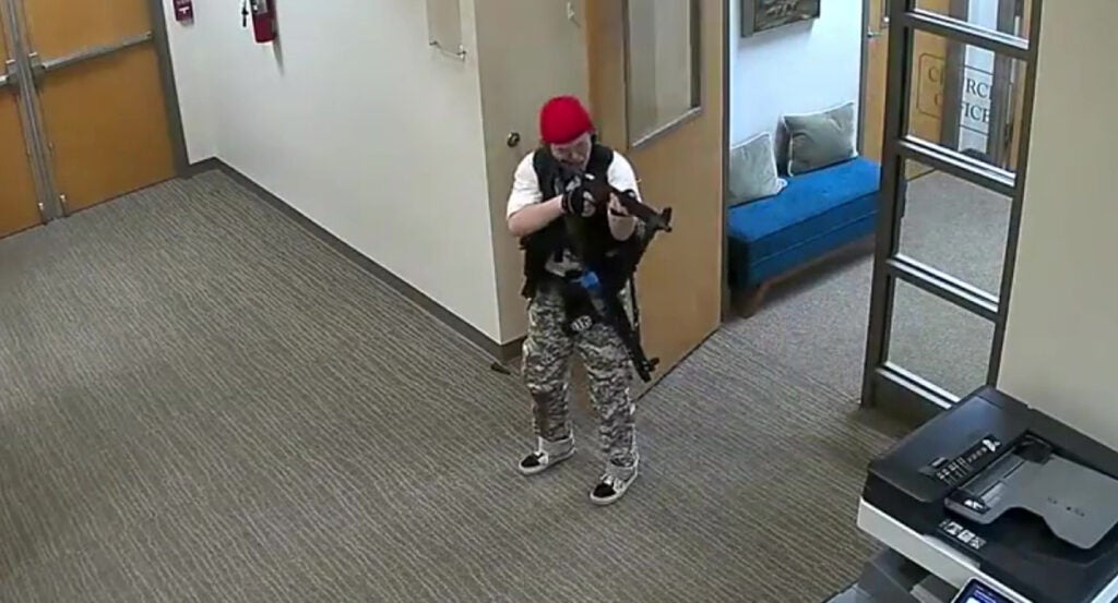 Audrey Hale in camouflage pants levels a gun at a printer in Nashville's Covenant School