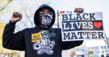 A female protester holds a sign reading "Black Lives Matter" as she also wears a face mask with "Black Lives Matter."