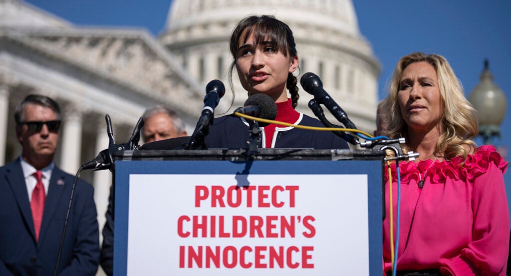 Detransitioner Chloe Cole stands in front of the Capitol behind a sign reading, "Protect Children's Innocence."