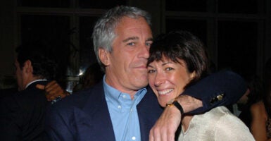 Jeffrey Epstein in a blue suit coat hugs Ghislaine Maxwell