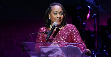 Fani Willis in a purple-y pink sparkly dress at The Root in front of a microphone