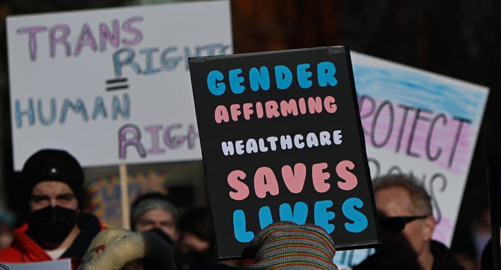 Protesters march with signs reading "Trans Rights Are Human Rights" and "Gender Affirming Healthcare Saves Lives"