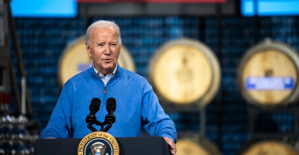 President Joe Biden stands behind a podium wearing a bright blue jacket.