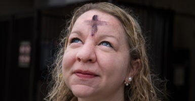 Woman looks at the sky wearing glitter ashes on her forehead for Ash Wednesday