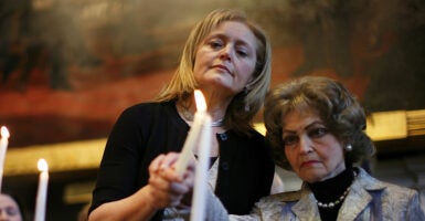 Katrina Lantos Swett stands with her mother, lighting a candle in memory of her late father, Tom Lantos.